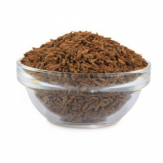 Clear glass bowl filled with cumin seeds on a white background