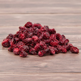 A pile of dried, freeze-dried red berries or raspberries on a rustic wooden surface.